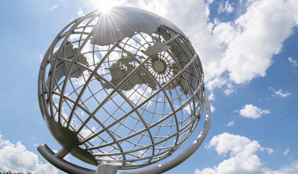 A close-up shot of the campus globe, backlit by a cloudy, blue sky.