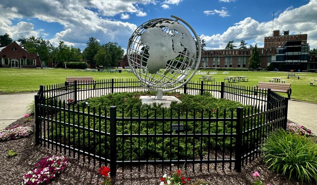 Campus globe in the summer with blue skies and colorful flowers.