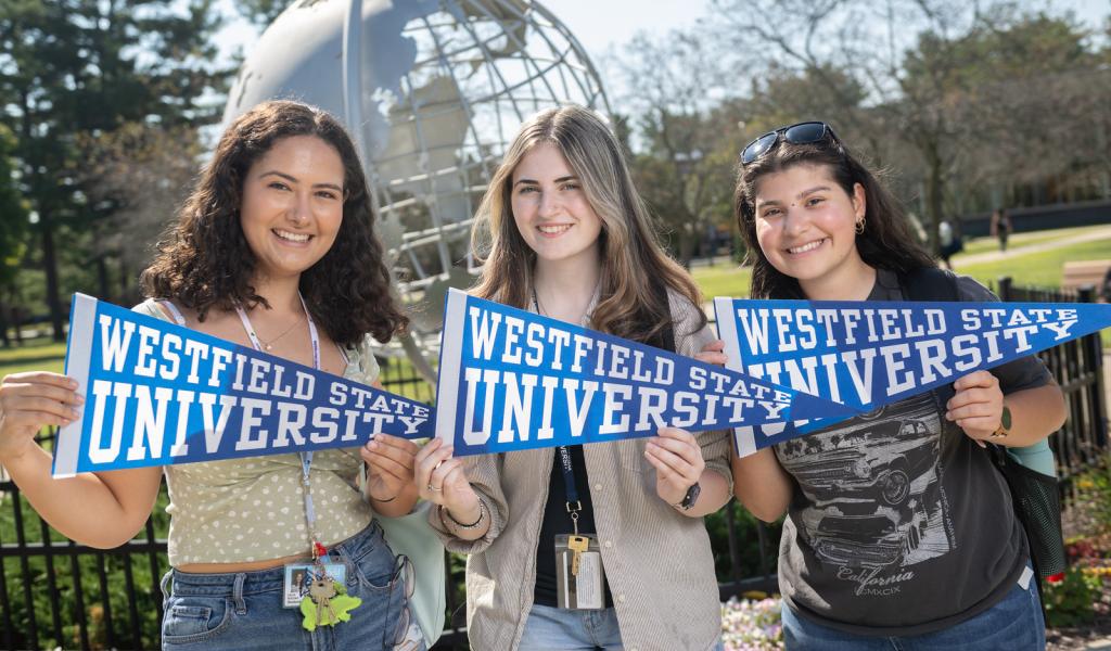 Three students holding Westfield State pennant flags on the first day of school.