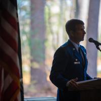 Colonel David Halasi-Kun stands next to an American flag while he addresses attendees for the 2023 Veteran's Day Ceremony.