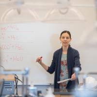 Professor Evanoski-Cole in front of classroom whiteboard.