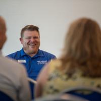 Director of Student Activities, Involvement, and Leadership, Matt Dellea. He is in a blue polo shirt and speaking to parents for New Student Orientation Day.