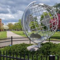 Globe in the spring with flowering trees behind it.