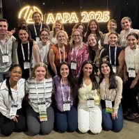 Students stand in a group in front of logo for AAPA 2025 Conference